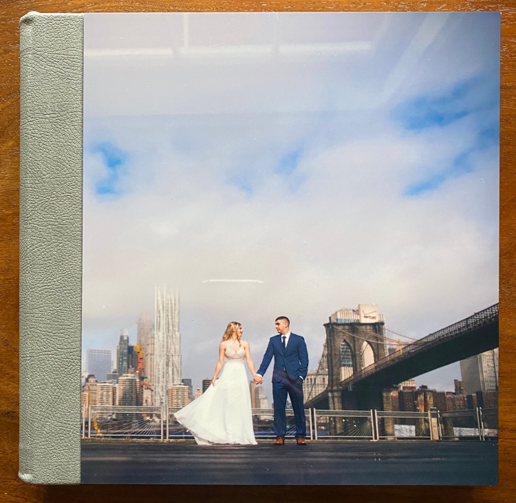 leather bound wedding album with photo on the front laying on wood table

